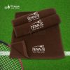 Khăn cotton màu nâu thêu chữ TENNIS trắng trải trên nền cỏ xanh