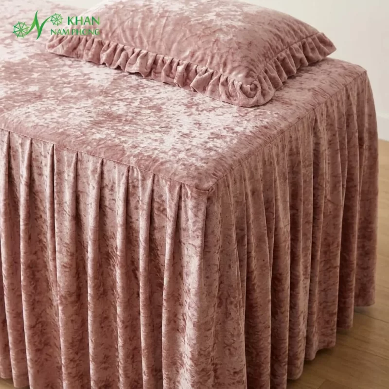 Cận cảnh bề mặt vải nhung tuyết hồng và váy xếp ly phủ chân ga trải giường spa