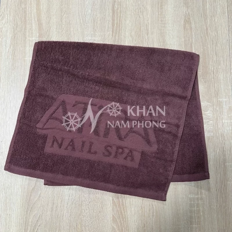 Cận cảnh khăn làm nail cotton dệt logo chìm ATIRA NAIL SPA màu nâu socola dập nổi mềm mịn tại Khăn Nam Phong