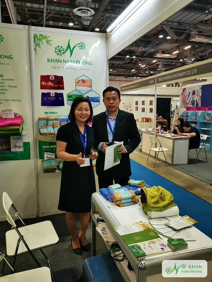 Lê Thị Nhung – Người Sáng Lập, Giám Đốc (Ceo) Khăn Nam Phong Lê Thị Nhung đứng cạnh bàn mẫu khăn bông trong gian hàng hội chợ Khăn Nam Phong