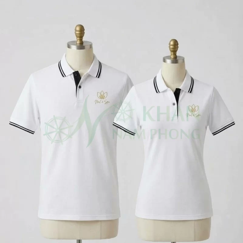 Áo Polo Đồng Phục Tiệm Nail Nam Nữ Màu Trắng Viền Đen Thêu Logo mặt trước: hai phom áo polo màu trắng tinh tế có viền sọc đôi đen ở cổ và tay áo, thêu logo hoa sen Nail & Spa ánh kim