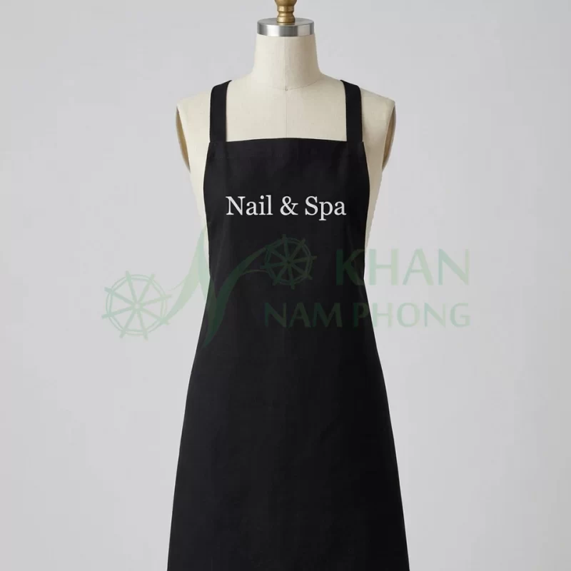 Tạp dề nail màu đen quai chéo mặt trước: yếm đen trơn, logo thêu trước ngực