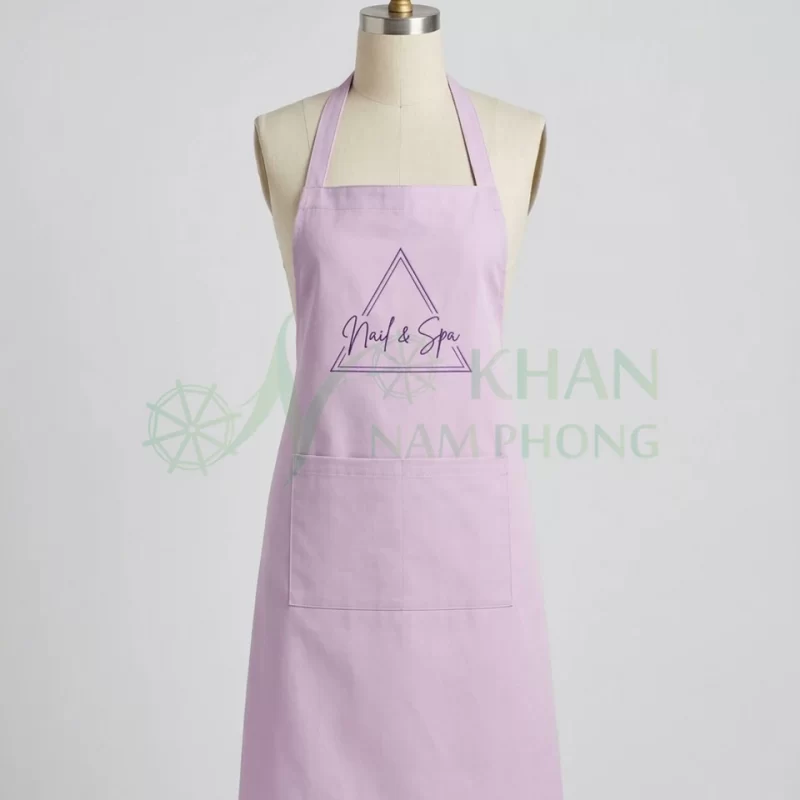 Tạp dề nail màu tím lilac mặt trước: yếm tím lilac, logo thêu trước ngực, túi lớn ngang bụng